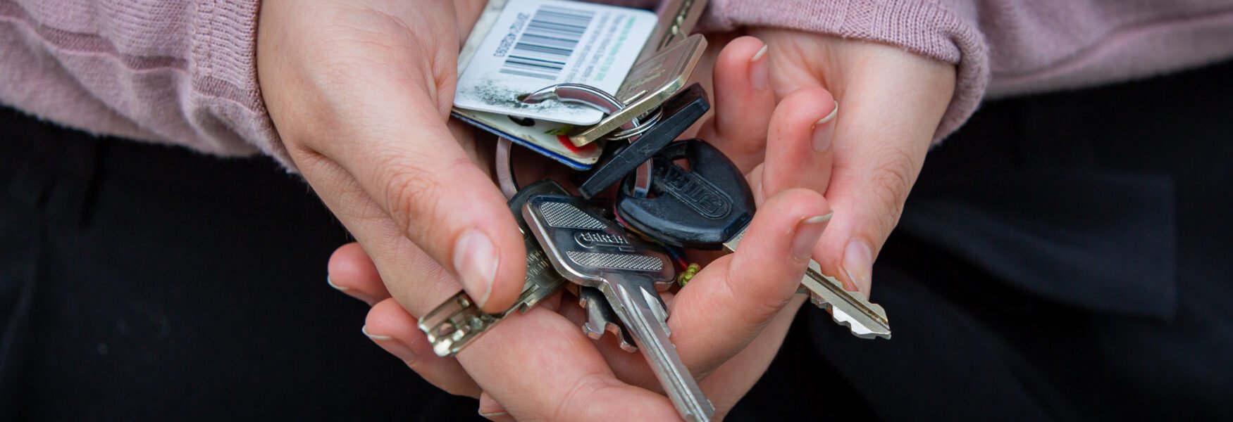 A bunch of keys being held in hands.